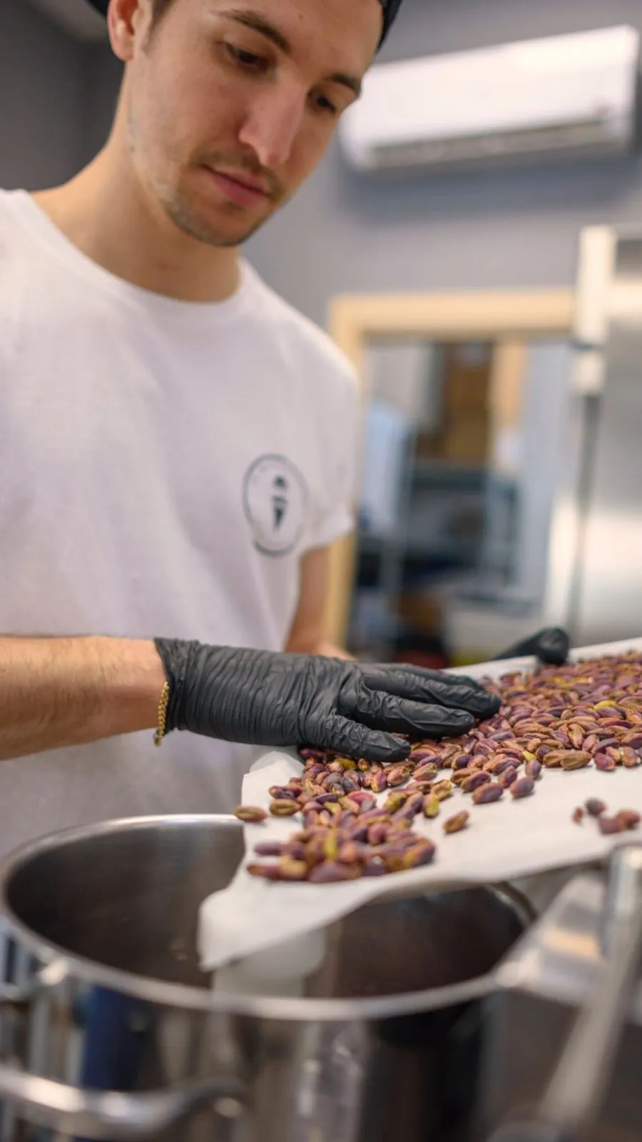 Gelatiere aggiunge i pistacchi durante la lavorazione in laboratorio